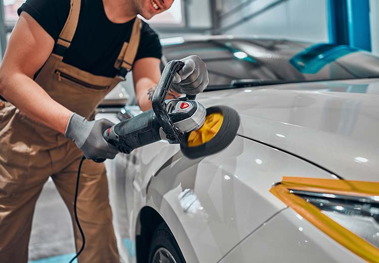 smiling man polishing a grey car