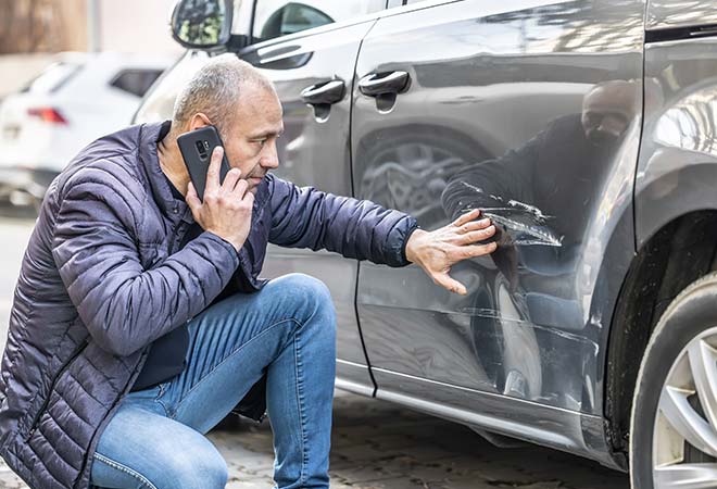 Man investigating car damage.