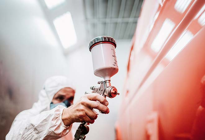 Car being painted red in a car paint shop.